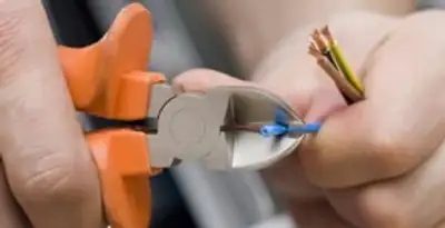 licensed electrician performing precise wire cutting and preparation during electrical service in Oklahoma City, OK